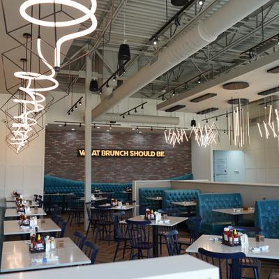 Interior features modern, geometric light fixtures and blue cushioned booths.