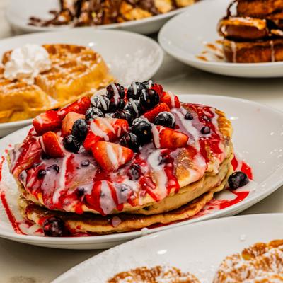 Stack of berry pancakes served alongside other breakfast dishes.