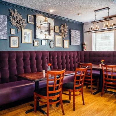 Interior, banquette seating and tables with chairs, wall decorated with lots of pictures.
