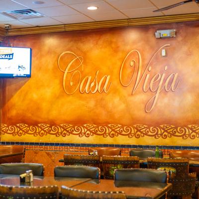 Interior of a restaurant with sign on a decorated wall.
