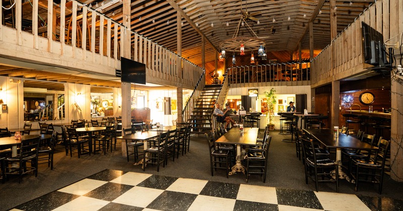 Interior, rustic eatery with wooden beams, tables, and a balcony