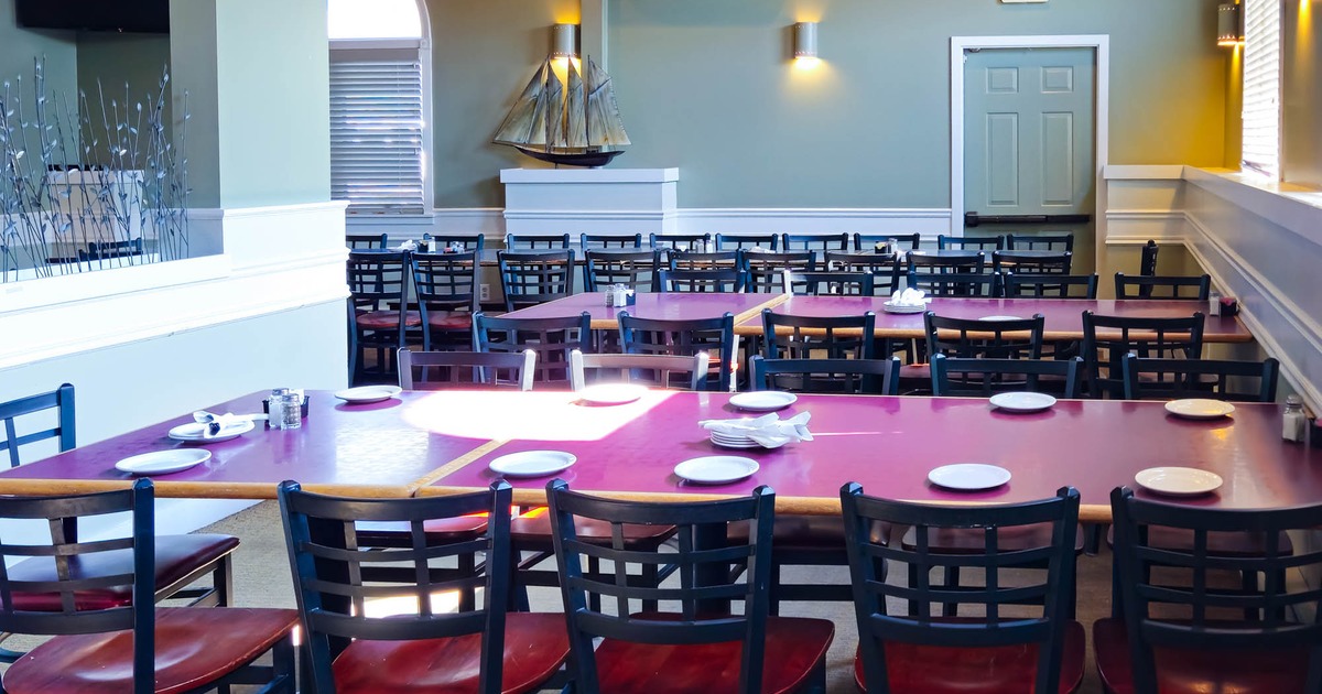 Interior dining area with tables, chairs, a model ship, and an air conditioning unit