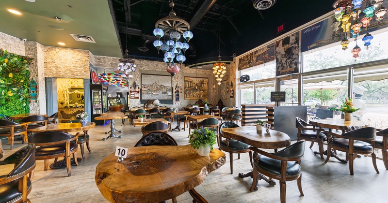Interior of a stylish and cozy seating area with dark leather chairs and wooden tables