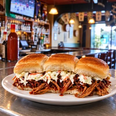 Three pulled-meat sliders topped with slaw on a white plate..
