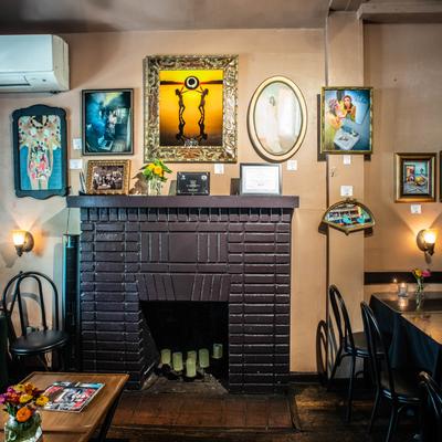 The interior, the fireplace mantel and framed paintings above.