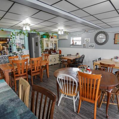 Interior with wooden tables, mismatched chairs, and string lights.
