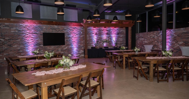 Interior, event space, wooden tables and chairs, subtle violet neon lighting on the wall