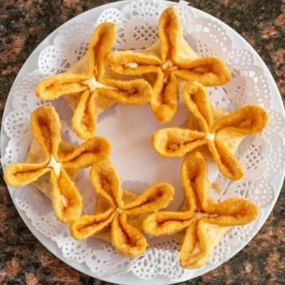 Cheese Rangoon arranged on a white lace plate.