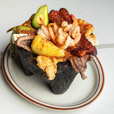 Molcajete featuring grilled steak, chicken, jumbo shrimp, chorizo and peppers.