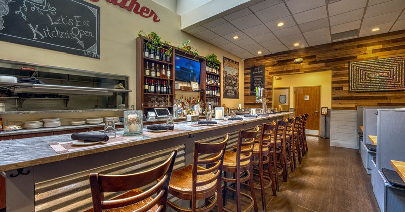 Interior, bar area, marble top bar with wooden stools, prep station and drink shelves