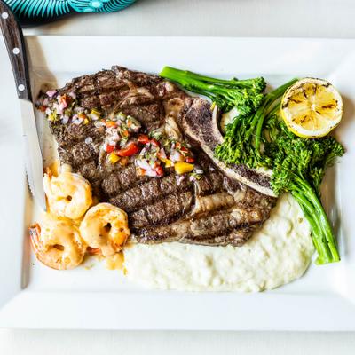 Grilled ribeye steak with mash potatoes, brocolini and chimichurri sauce.