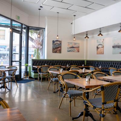 Interior, whicker style chairs and wooden tables, booth seating, art prints on the walls.