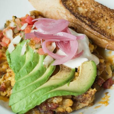 Egg scramble with avocado slices, onions, and toast.