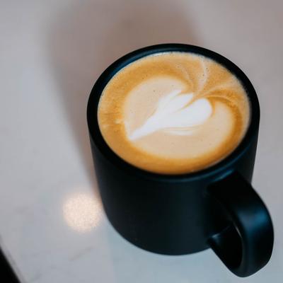 Latte in a black coffee mug with heart-shaped latte art.