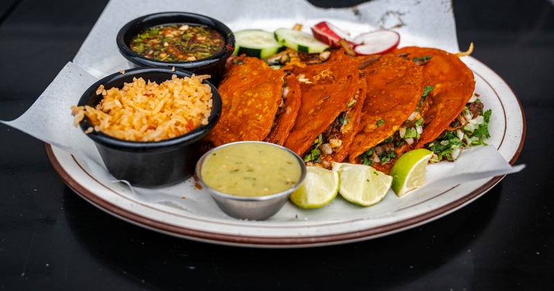 Birria tacos served with consomme and various sides