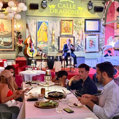 A table of four people eating while the singer sings boleros at the stage.