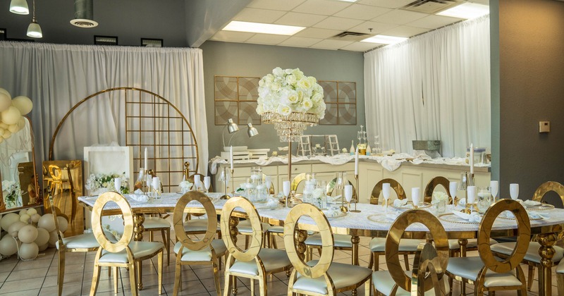 Elegant event space with a long table, gold chairs and white floral