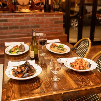 Interior, a dining table set with various plates of food and red wine.