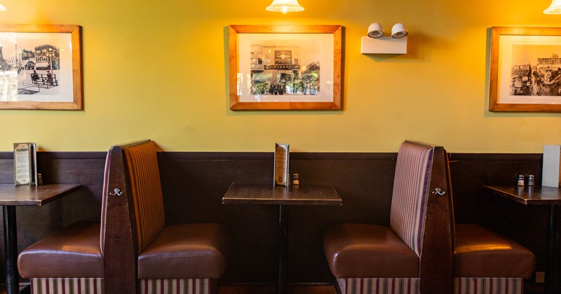 Inside, booths with striped upholstery, framed historical photographs, and dark wood furnishings