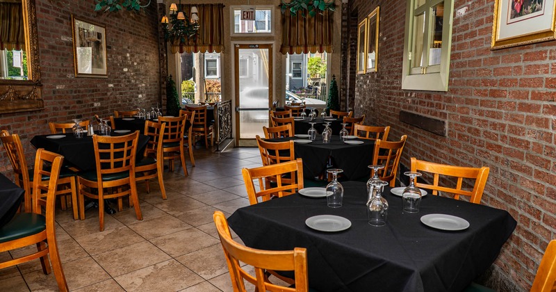 Cozy restaurant interior with brick walls, wooden tables and chairs, black tablecloths