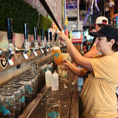 A bartender pouring a pint of draft beer.