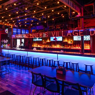Bar area with a counter illuminated by blue LED accent lighting, stools and signage.