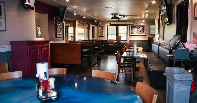 Interior, checkout counter, seating booths, multiple tv screens on walls