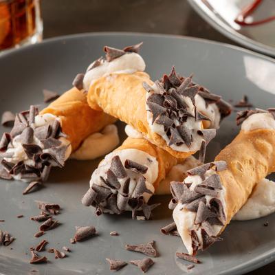 Four Cannolis with chocolate flakes.