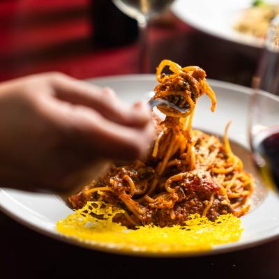 A hand holding a fork with spaghetti.