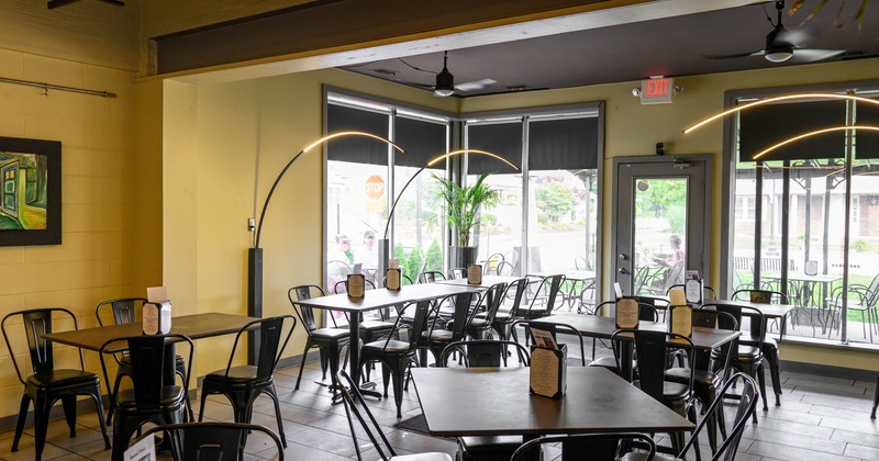 Interior, black metal tables and chairs, large windows, and curved floor lamps