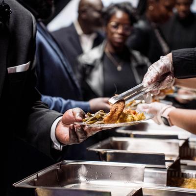 Employee serving a customer with food at the buffet table.