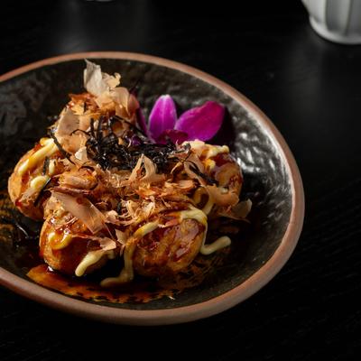 Grilled octopus balls saved on a table with floral display.