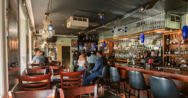 Interior with a mix of table and counter seating and a backbar filled with various liquor bottles