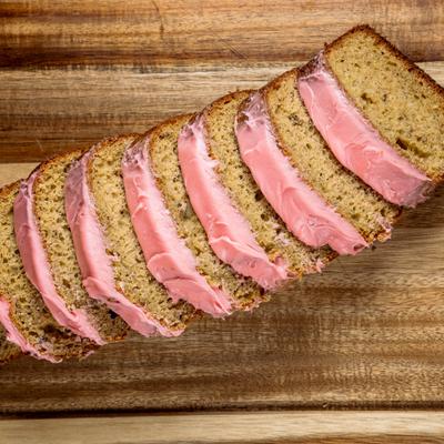 Strawberry banana nut bread loaf sliced on a wooden board.