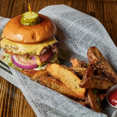 Cheeseburger with vegetables served with seasoned potato wedges.