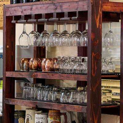 Rustic dark wood bar cart with hanging wine glasses and multi-tier shelves.