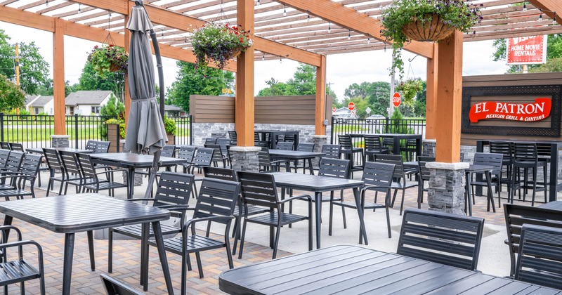 Outdoor patio, black metal tables and chairs under a wooden trellis