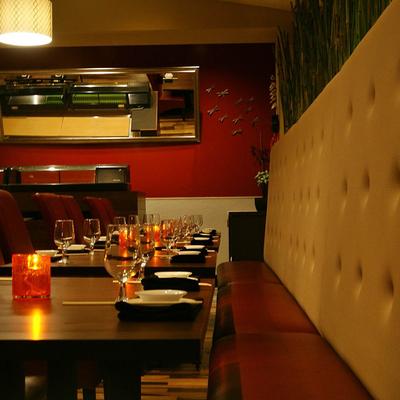 Restaurant interior, high back banquette seating with tables ready for dining.