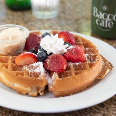Belgian waffle topped with fresh berries, whipped cream, and powdered sugar.