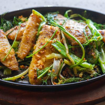 Cha Ca featuring pan-fried white fish served with fresh dill and spring onions.