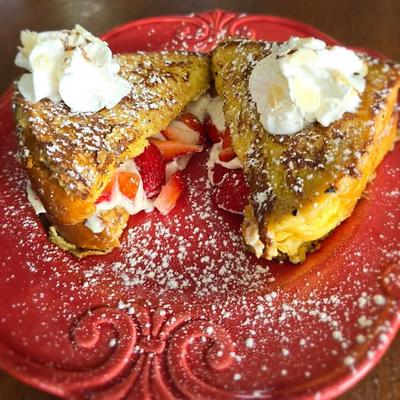 Strawberry cheesecake French toast topped with whipped cream and powdered sugar.