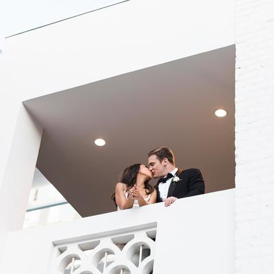 The bride and groom kissing on the balcony.