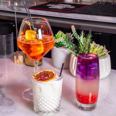 Colorful cocktails on a table with potted plants nearby.