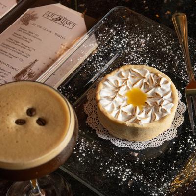 Lemon meringue tart with espresso martini and wine list on a table.