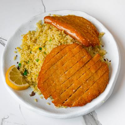 Pork katsu served with fried rice and a lemon wedge.