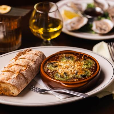 Traditional escargot served with baguette, drinks and food in the background.