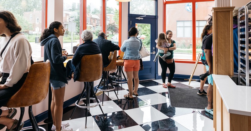 Patrons stand and sit at high-top stools inside