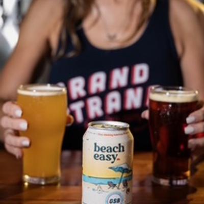 person holding 2 glasses of beer with can of beer in the middle.