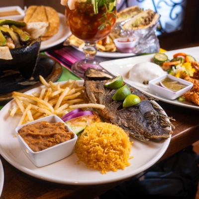 Whole fried tilapia fish served with fries, rice, beans and lime wedges.