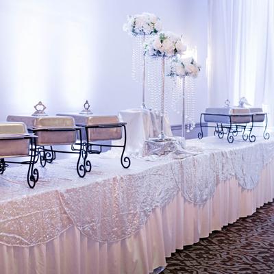 Elegant buffet table with chafing dishes and floral decor.